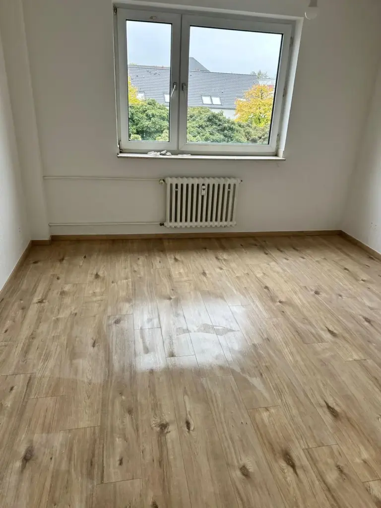 Fertig verlegter Boden in heller Holzoptik in einem Zimmer mit Fenster